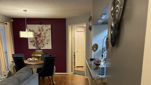 A modern living room with a grey sofa, a dining table with chairs, and a kitchen area with a countertop and sink. - Quaint, Quiet, and Comfortable Home Away From Home (Hoover)