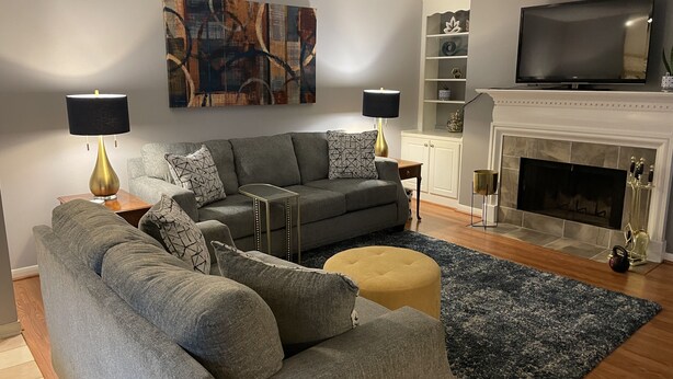 A modern living room with a grey sofa set, two floor lamps, a fireplace, and a flat-screen TV. - Quaint, Quiet, and Comfortable Home Away From Home (Hoover)