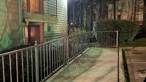 A nighttime view of a two-story house with a balcony, a gated entrance, and a paved driveway. - Quaint, Quiet, and Comfortable Home Away From Home (Hoover)