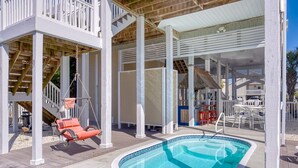 Un espace piscine doté d’une chaise suspendue, d’une terrasse couverte et d’un escalier menant à un niveau supérieur.