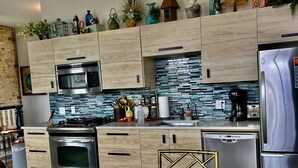 Una cocina moderna con armarios de madera, electrodomésticos de acero inoxidable y un salpicadero de azulejos.