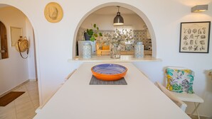 Et moderne køkken med en central ø, et spisebord med en skål, og udsigt til spiseområdet.