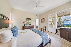 Une chambre avec un lit, un ventilateur de plafond, une commode, une chaise et une vue sur l’extérieur grâce à une porte-fenêtre coulissante.