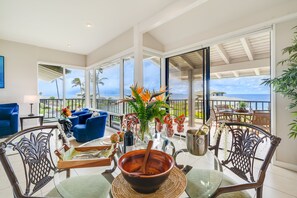 Enjoy ocean views from the large window, surrounded by comfortable seating and a dining area with a decorative centerpiece.