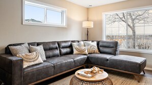 A living room with a dark leather sectional sofa, a round coffee table, and a floor lamp. - 🌞 Meridian BNB - 4BR/2.5BA Huge Backyard: Near Eagle, Star, Boise, The Village (Meridian)
