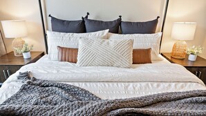 A neatly made bed with a gray knitted blanket, multiple pillows, and two bedside tables with lamps and small potted plants. - 🌞 Meridian BNB - 4BR/2.5BA Huge Backyard: Near Eagle, Star, Boise, The Village (Meridian)