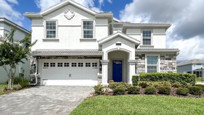 A two-story house with a garage, a blue front door, and a well-maintained lawn.