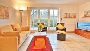 A living room with a sofa, chairs, a coffee table, a TV, and artwork on the walls. - Hanseatic Residence Apartment 4 - Hanseatic Residence (Scharbeutz)