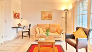 A living room with a sofa, a coffee table, a chair, and a lamp. - Hanseatic Residence Apartment 4 - Hanseatic Residence (Scharbeutz)