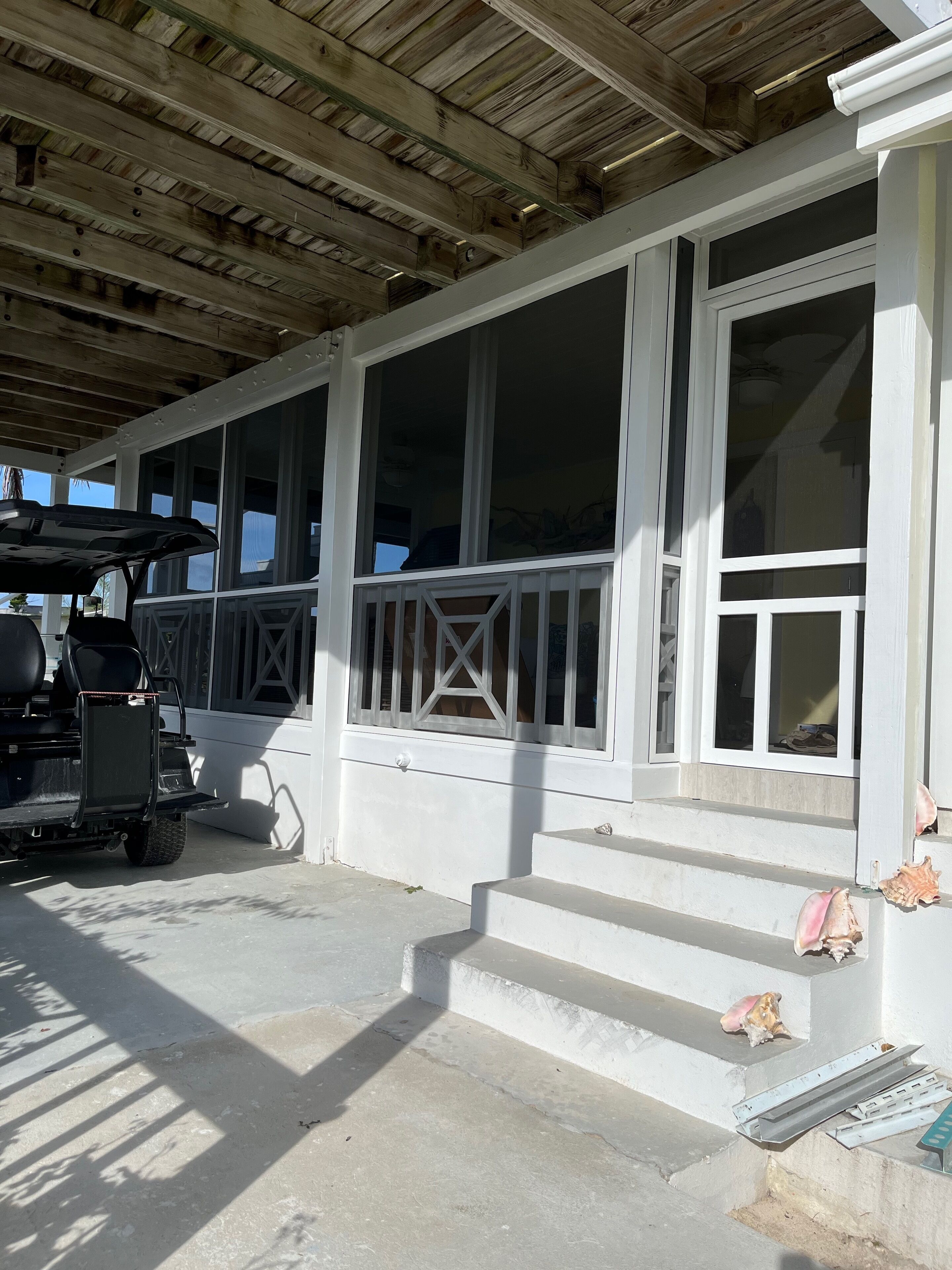 A covered porch with a wheelchair accessible ramp, large windows, and a wooden ceiling.