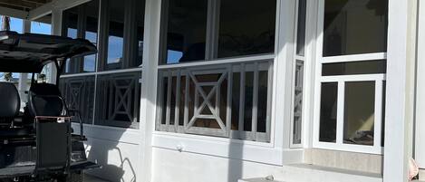 A covered porch with a wheelchair accessible ramp, large windows, and a wooden ceiling.
