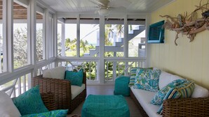 A covered porch with wicker furniture and teal cushions, overlooking a tropical landscape. - Tranquility reigns at Talisman (Elbow Cay)