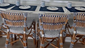 A dining area with a view of the ocean, featuring a white table with blue placemats, striped chairs, and a ceiling fan. - Tranquility reigns at Talisman (Elbow Cay)