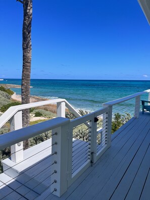 A wooden deck with white railings overlooking a beach with clear blue water and a palm tree. - Tranquility reigns at Talisman (Elbow Cay)