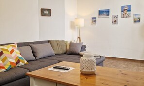 Un salon moderne avec un canapé d’angle gris, une table basse en bois et un lampadaire.