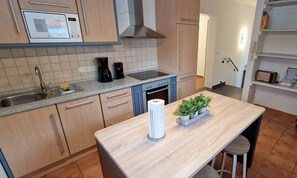 Uma cozinha moderna com micro-ondas, cafeteira e uma pequena mesa com uma planta.