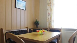 Un comedor con una mesa y sillas de madera, un cuadro en la pared y una planta en maceta.