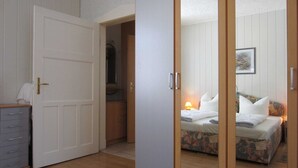 Un dormitorio con una cama, una mesita de noche, un armario y un baño visible a través de una puerta abierta.