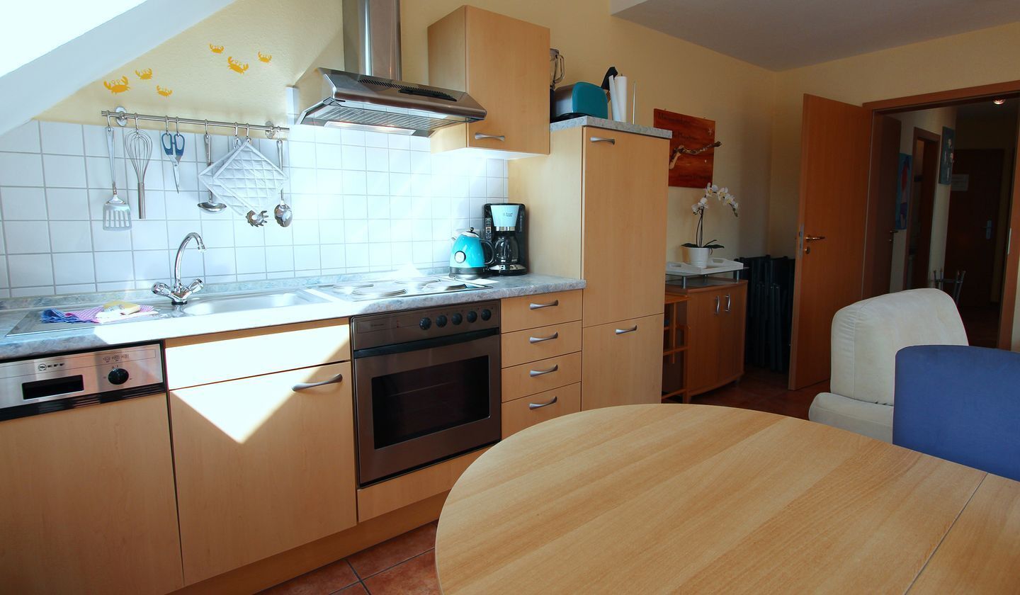 A kitchen with a stove, oven, coffee maker, and hanging utensils.
