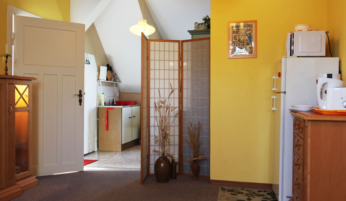 A kitchen with a wooden cabinet, a white refrigerator, and a red rug.