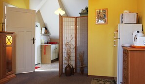 A kitchen with a wooden cabinet, a white refrigerator, and a red rug.