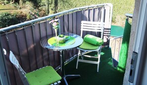 A small outdoor seating area with a round table, two chairs, and a decorative vase.