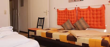 Una habitación de hotel con cama, una silla y un cabecero fijado a la pared.