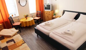 Habitación de hotel con dos camas, televisión, una mesa con silla y ventana con cortinas.