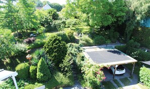 A garden with a gazebo, a car, and a pond.