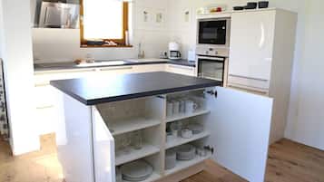 Eine kompakte Küche mit integriertem Kochinsel, weißen Schränken, einer Mikrowelle und einer Kaffeemaschine.