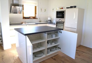Eine kompakte Küche mit integriertem Kochinsel, weißen Schränken, einer Mikrowelle und einer Kaffeemaschine.