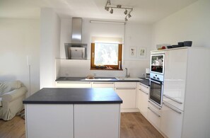 A modern kitchen with white cabinets, a black countertop, a built-in oven, and a window above the sink.
