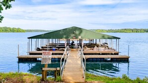 Un hangar à bateaux avec un quai couvert, un panneau indiquant qu’il s’agit d’une propriété privée et une vue dégagée sur le lac.