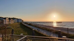 Vista costera con un paseo marítimo, un muelle y edificios a lo largo de la orilla.