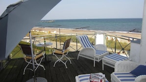 Terraza con mobiliario de mimbre y una mesa, con vista a una playa y al océano.
