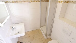 A bathroom with a shower, sink, toilet, and a mirror. - Meeresblick - Welcome to the vacation apartment Meeresblick in Kühlungsborn (Kühlungsborn)