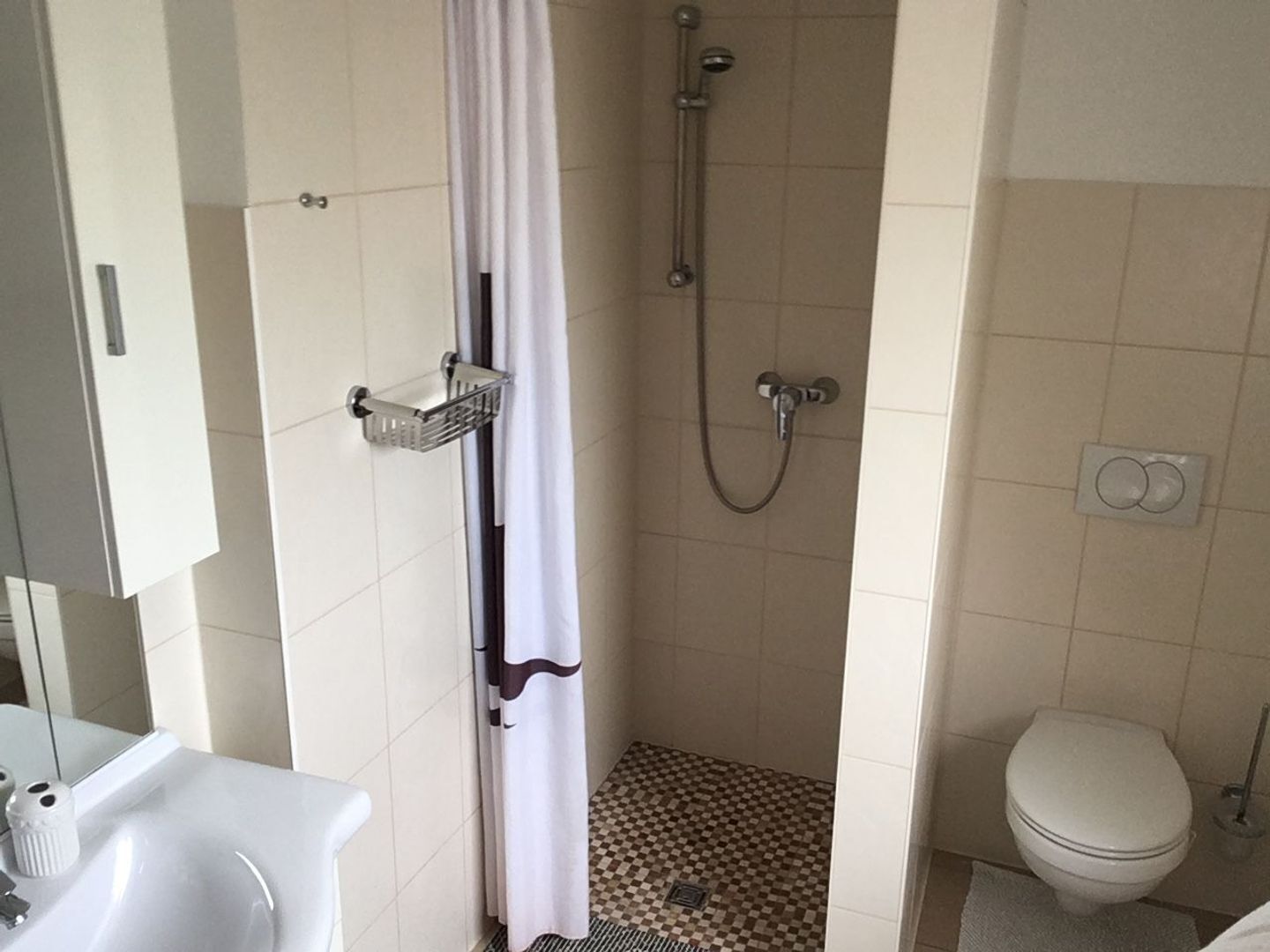 Une petite salle de bain avec une douche, des toilettes et un lavabo.