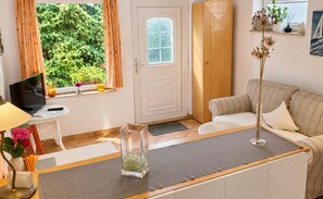 Un salon avec un canapé, une table basse, un téléviseur et une fenêtre avec des rideaux.