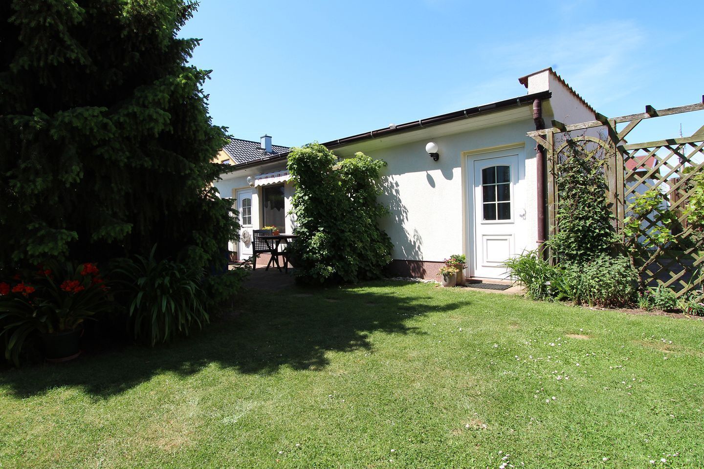 A house with a well-maintained lawn, a wooden fence, and a door with a window.