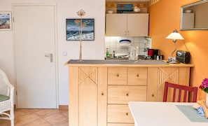 Une cuisine compacte avec un coin repas, une porte blanche et un tableau encadré au mur.