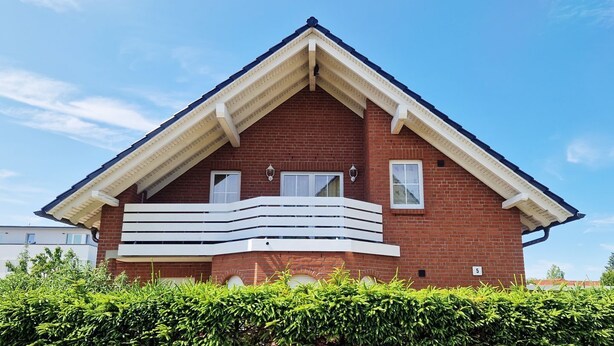 A red brick house with a gabled roof and a balcony. - Am Obstgarten - Comfortable vacation apartment with covered balcony near the beach in (Kühlungsborn)