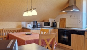 Une cuisine compacte avec un coin repas, équipée d’une cuisinière, d’un four à micro-ondes et de divers appareils électroménagers.