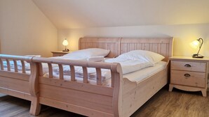A wooden bed with a headboard, two bedside tables, and a nightstand with lamps. - Am Obstgarten - Comfortable vacation apartment with covered balcony near the beach in (Kühlungsborn)