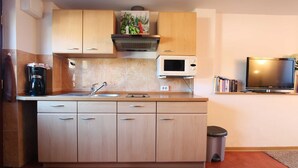 Una cocina con armarios de madera, microondas, cafetera y cubo de basura.