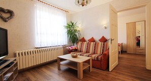 A cozy living room with a sofa, a coffee table, a TV, and a radiator.