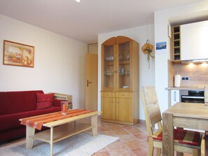 Ein Wohnzimmer mit einem roten Sofa, einem Holztisch mit einem Glas und einem Schrank mit Glastüren.