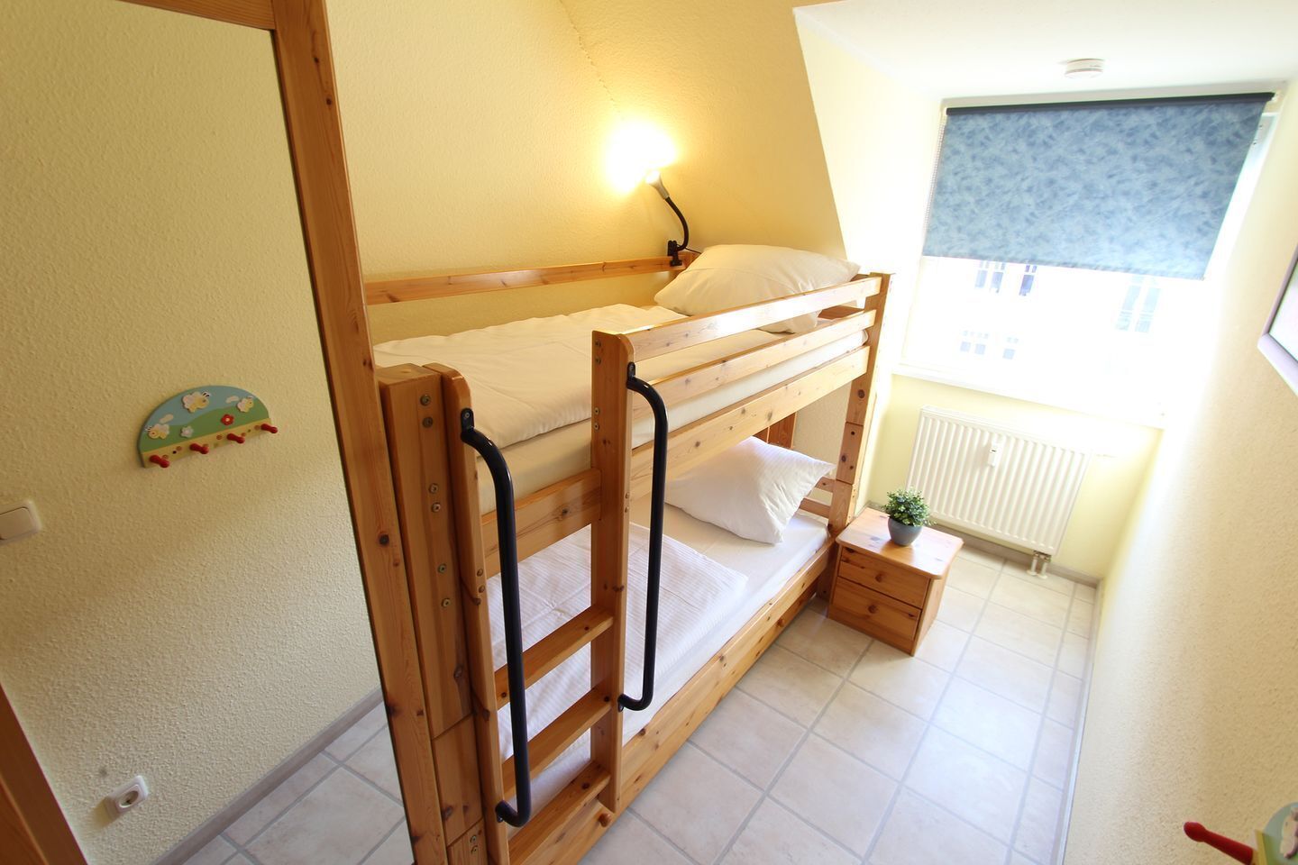 Une chambre avec un lit superposé, une table de chevet, une lampe et une fenêtre donnant sur un beau paysage.