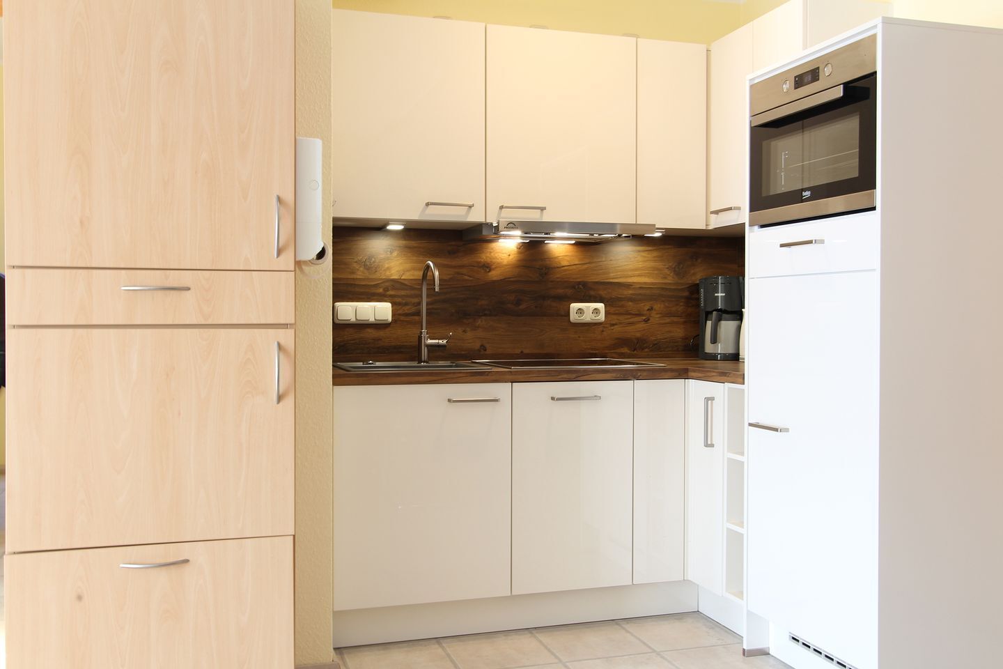 Eine moderne Küche mit Holzschränken, einer Edelstahl-Spüle und einem eingebauten Backofen.