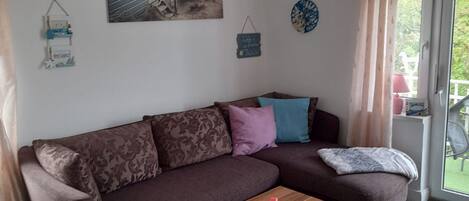 Una sala de estar moderna con un sofá marrón, una mesa de centro de madera y un ventanal con cortinas.