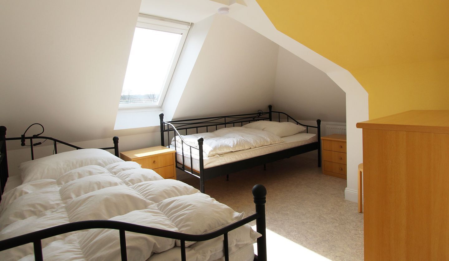 A bedroom with a loft bed, a window, and a wooden dresser.